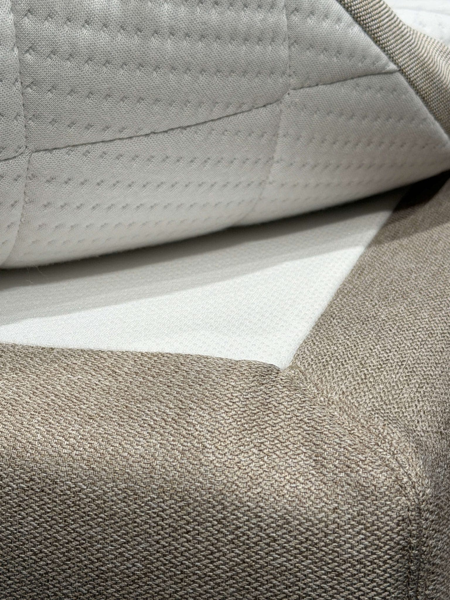 Angehobene Ecke des Toppers mit sichtbarer Anti-Rutsch-Schicht zwischen Topper und Bettbezug
