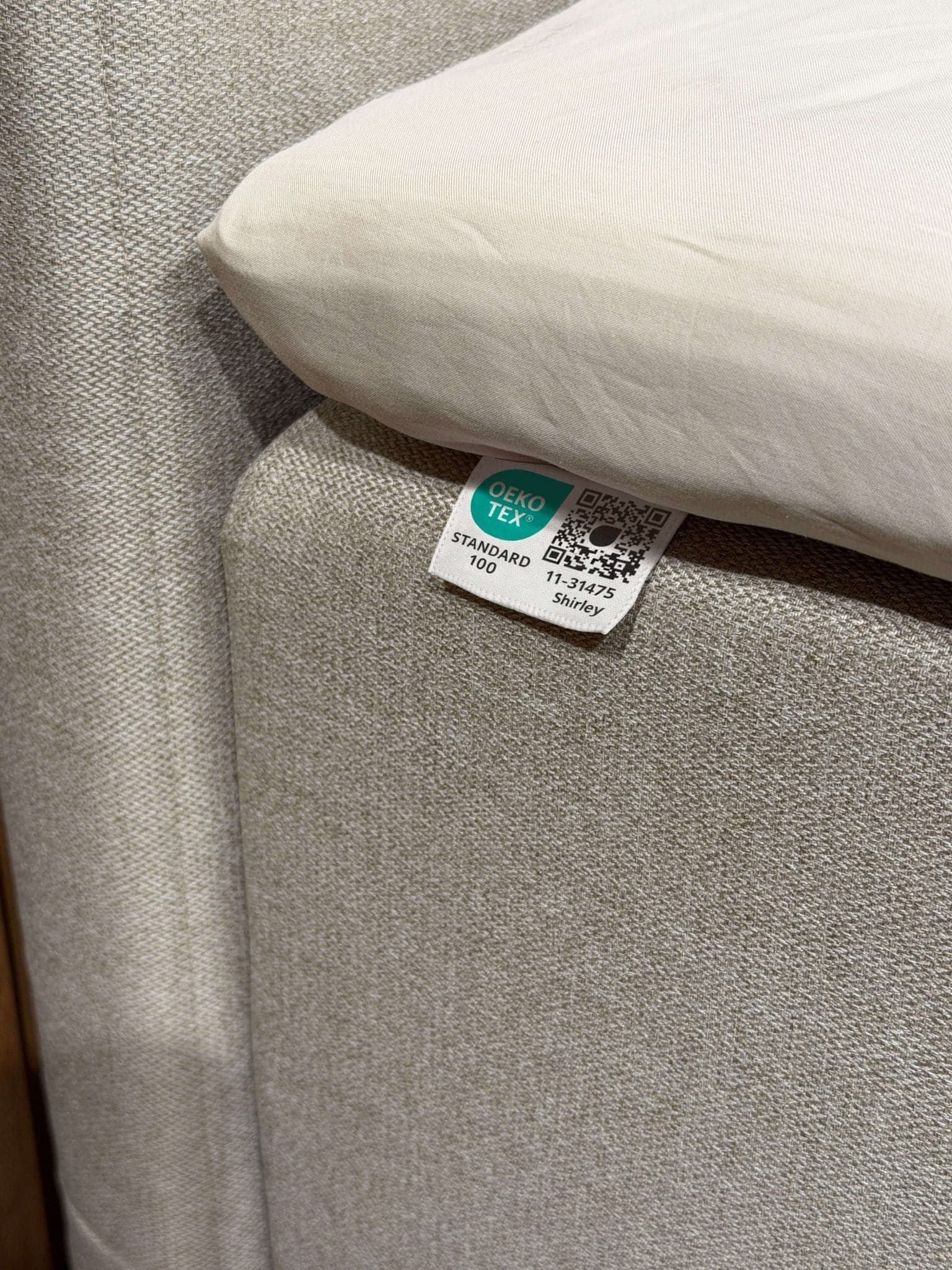 Unter dem Bettlaken auf den beigefarbenen Stoff des Bettes genähtes OEKO-TEX® STANDARD 100-Label
